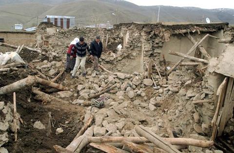 Residents walk through the remains of a collapsed building in Eastern Turkey